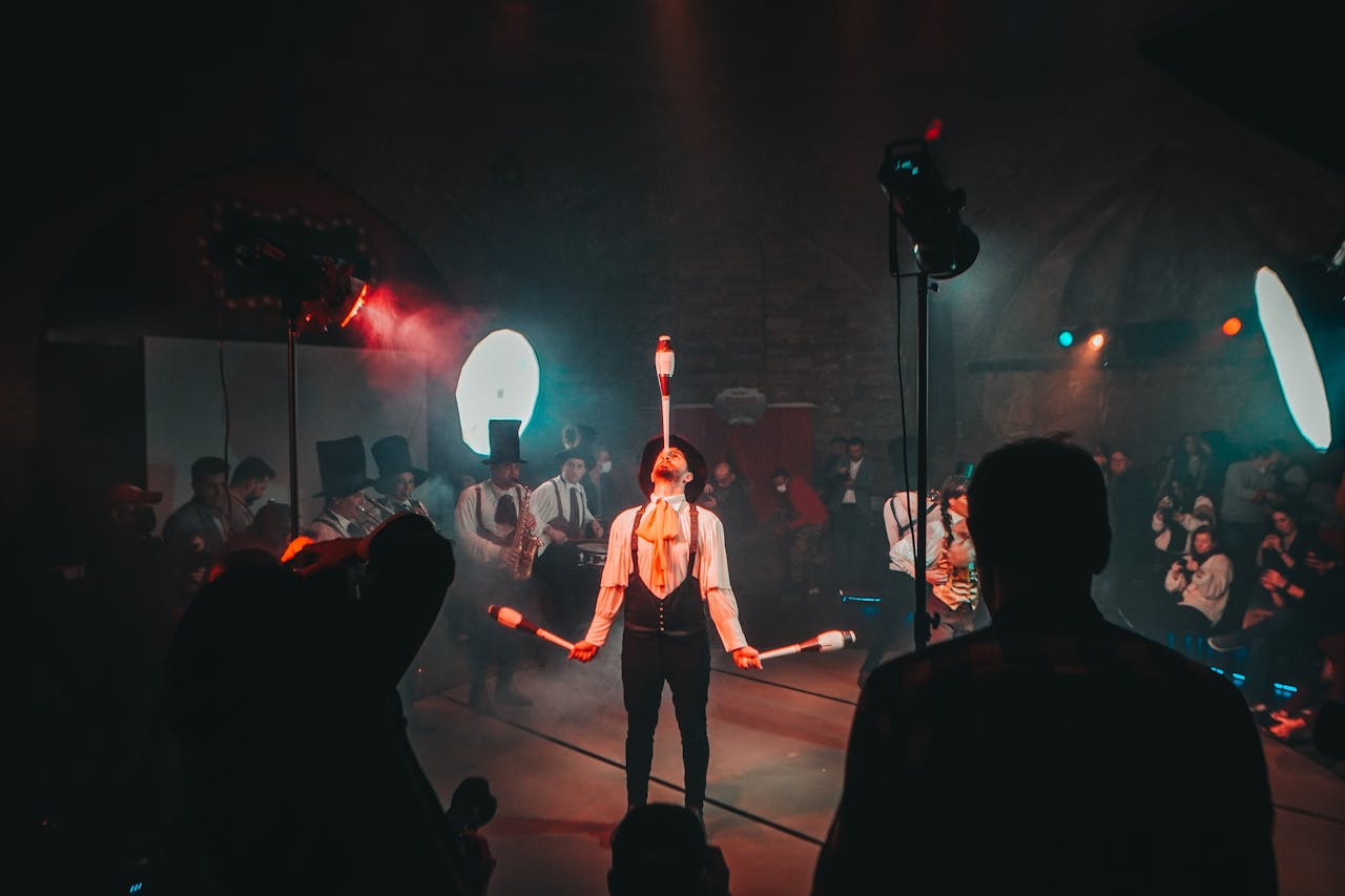 A mesmerizing circus juggler performs under dramatic lighting during a lively festival.